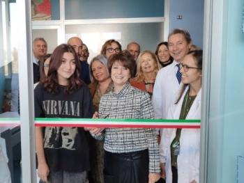 Taglio del nastro per l'inaugurazione della scuola in ospedale ad opera della maestra e di una giovane paziente